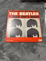 Front of the original motion picture soundtrack vinyl LP by The Beatles for 'A Hard Day's Night' with red and white cover and four band member photos.