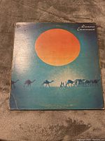 Front cover of Santana Caravanserai LP showing desert scene with large orange sun and camels.