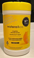 Front view of cylindrical yellow and white container of watera&co. disinfectant wipes with label showing 160 wipes and citrus scent.