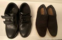 Pair of black shoes and slippers side by side on a white surface, showing overall condition and style