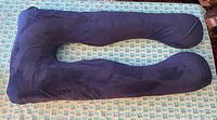 Top view of the navy blue velour side of the full body U-shaped pregnancy pillow laid flat on patterned fabric.