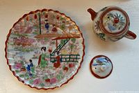 Top view of teapot and separately placed lid with floral and bird motifs and gold detail