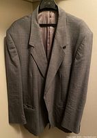 Front view of Moores men's grey suit jacket with subtle stripes, hung on hanger against beige background.