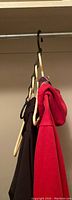 Five black Space Saver hangers showing their vertical design holding multiple pieces of clothing on a closet rod, demonstrating space-saving functionality.