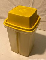 View of entire Tupperware pickle drawer dispenser highlighting yellow lid and clear rectangular body.