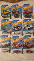 Photo of 9 Hot Wheels cars in original packaging cards showing front view and cars including the yellow Pagani Zonda R.
