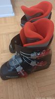 Top and inside view of pair of Salomon ski boots showing red interior lining and buckles.