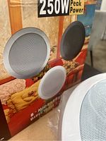 Photo shows the front of the speaker packaging with 250W peak power label and images of the round in-ceiling speakers with grille covers.