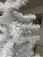 Close-up image showing the white artificial pine branches with no lights on to display the texture and color of the tree.