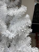 Close-up of white artificial tree branches with plastic needles.