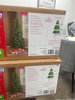 Boxes of two artificial Christmas trees labeled as 6 ft Wesley Pine with product specifications.