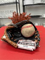 Black and brown leather Rawlings baseball mitt labeled 'Ready to Play' with a used baseball inside.