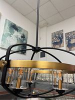 Close-up of the light fixture showing gold metal circular frame and clear glass shades with filament bulbs inside.