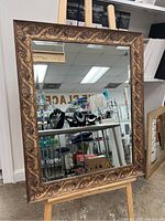 Full view of the rectangular mirror on an easel showing the ornate frame and clear reflective surface.