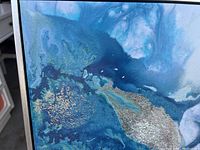 Close-up of blue, gold, and white fluid art pattern showing texture and metallic highlights.