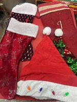 Overview photo showing three Christmas stockings and one red Santa hat with light bulb decorations.