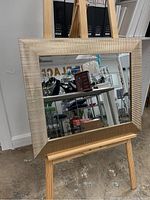 Full view of rectangular gold framed mirror on easel, showing reflective surface and frame texture.