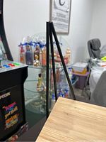 Side view of a single black metal frame hanging bookshelf showing the metal support structure and light wooden shelf below it.