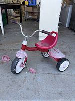 Front three-quarter view of the kids tricycle showing the plastic seat, handlebars, and the pedals on the front wheel.