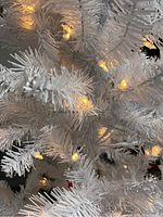 Close-up photo showing warm white LED lights on white artificial pine needles.