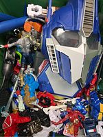 Photo showing mixed toys and action figures including a large Optimus Prime head and various Marvel characters.