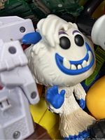 Close-up of white and blue yeti action figure showing details of face, teeth, and blue hands