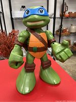 Front view of the 12 inch Leonardo TMNT figure showing detailed green skin, blue mask, and brown straps on orange shell chest plate.