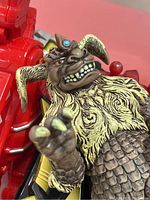 Close-up of a brown fantasy creature action figure with blue eye and detailed fur and armor features.