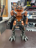 Front view of large brown and grey Transformers robot toy showing full body and clawed feet