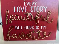 Front view of the red rectangular wall sign showing the full quote with white text and gold wire cursive words.