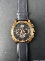 Front view of Bulova men's quartz chronograph watch showing black dial, sub-dials, date window, and black leather strap.
