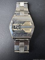 Front view of vintage Caravelle Digimatic jump hour watch showing rectangular case, digital time display, and metal bracelet with signs of wear and scratches.