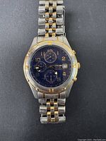 Front view of vintage Citizen men's quartz chronograph watch with blue dial and two-tone bracelet showing wear and details of dial and hands.