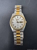 Front view of Seiko quartz watch showing face with day/date and two-tone metal bracelet.