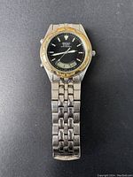 Full view of Seiko quartz watch on black background showing stainless steel bracelet, black dial, and bezel with wear.