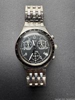 Front view of vintage Swatch men's chronograph watch showing black dial with three subdials and metal bracelet.