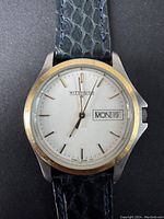 Front view of the vintage Wittnauer men's quartz watch showing gold-tone bezel, white dial, Wittnauer logo, and day-date indicator.