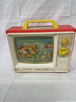 Front view of the toy television showing the river boat scene with characters and ducks.