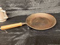Full view of cast iron frying pan with wooden handle showing overall condition.