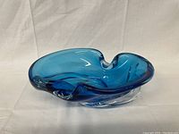 Blue Chalet art glass bowl with organic curved edges and central swirl design shown from an angled side view.