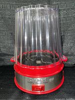 Front view of the Cuisinart EasyPop popcorn maker showing the clear plastic lid and red and stainless steel base.
