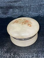 Top and angled view showing the round alabaster trinket box with painted flower decoration and metal band hinge