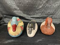 All three wooden duck decoys arranged side by side, showing the front and top views and detailing on paint.