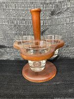 Front angled view of wooden condiment caddy showing three clear glass inserts and vertical handle.