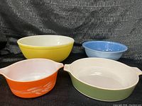 Four vintage Pyrex bowls displayed together, showing variety of colors and styles