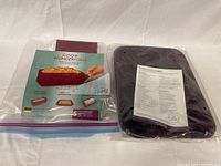 New in original packaging silicone muffin bakeware with instruction sheet visible through clear plastic.