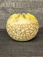 Front and side view of vintage yellow art glass vase showing floral and gold geometric pattern.