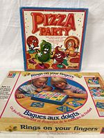 Pizza Party and Rings on your Fingers game boxes shown stacked with colorful box art and branding visible.