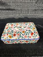 Porcelain playing card box lid with colorful floral and bird design.