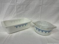 Photo showing two vintage Pyrex baking dishes with blue snowflake pattern, one oblong and one round with lid.